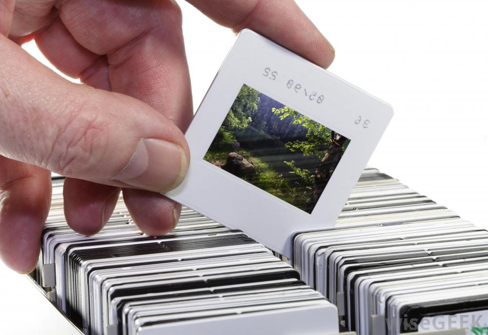 A hand pulling out a photo-slide from a box of photo-slides.